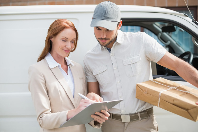 dispatch driver holding a package and a woman customer signing order received delivery form